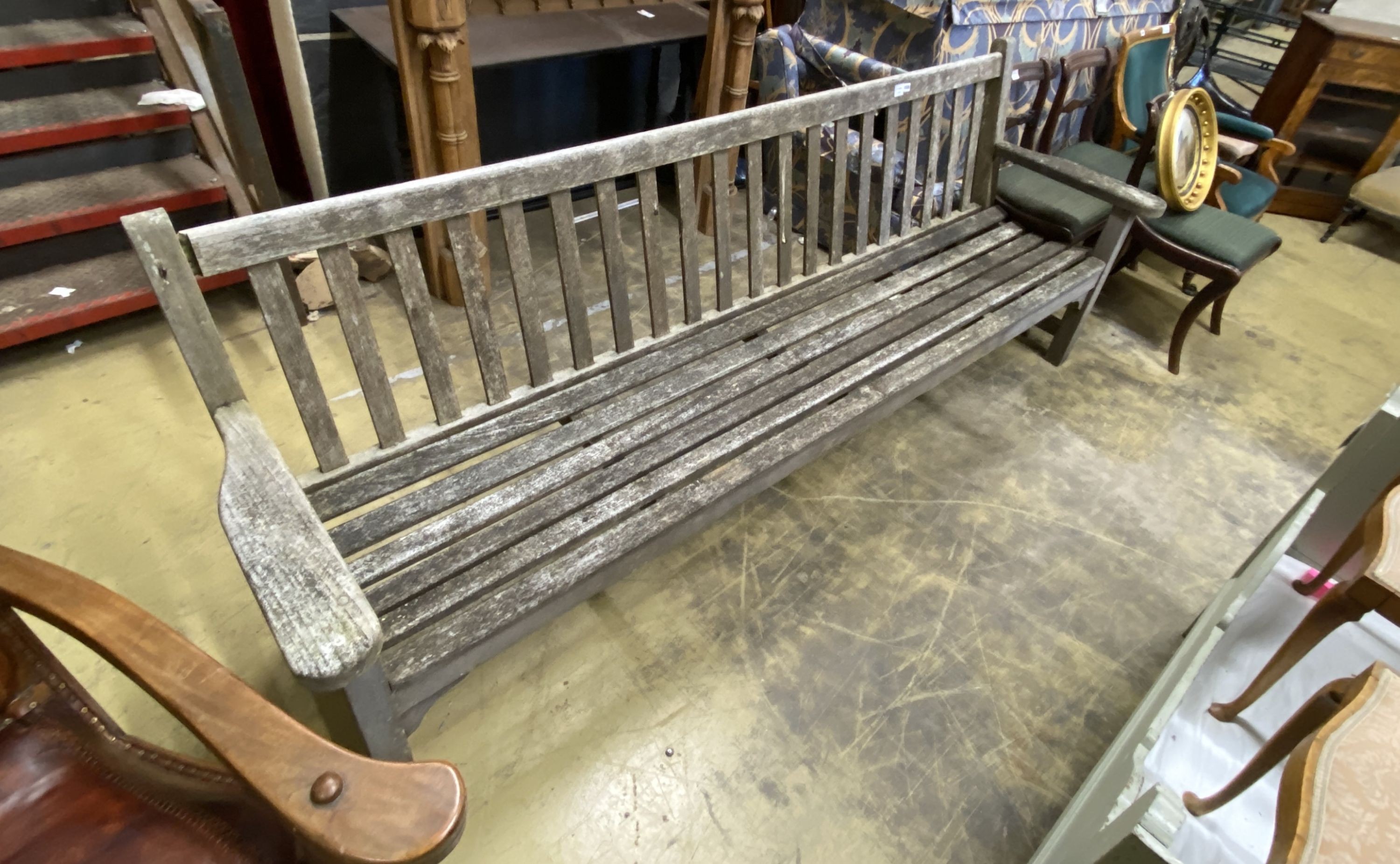 A large weathered teak slatted garden bench, length 254cm, depth 51cm, height 97cm